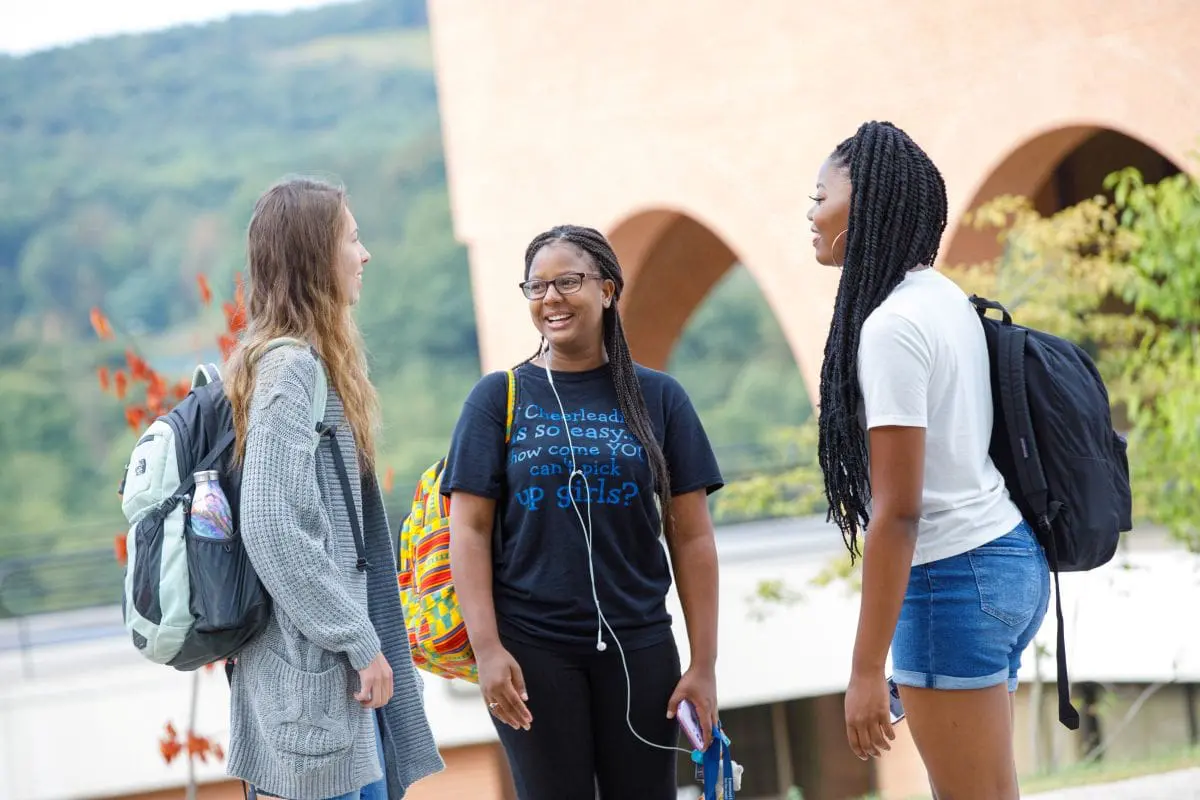 three students on campus having a conversation outside