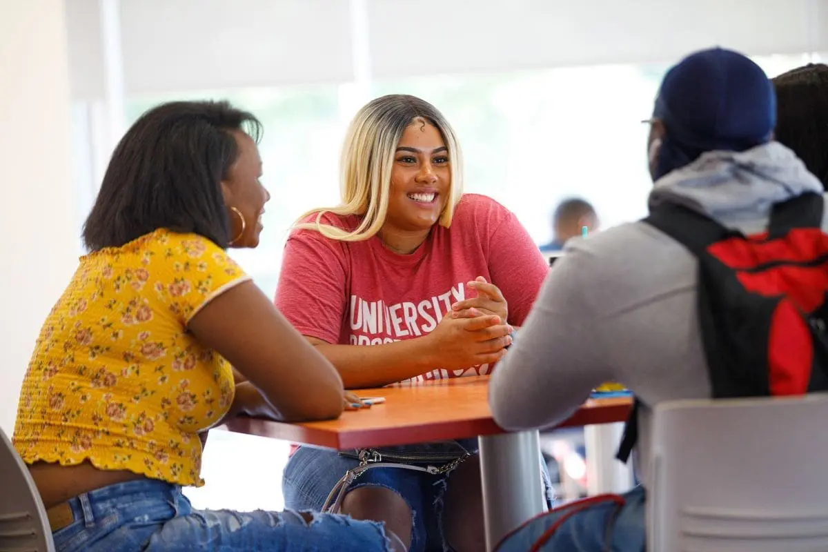 3 students sitting at a table conversing
