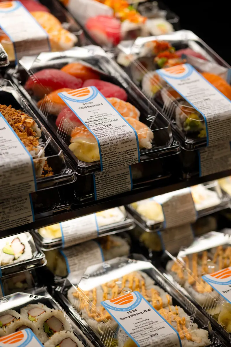 neatly packaged sushi trays displayed on refrigerated supermarket shelves, ready for purchase.