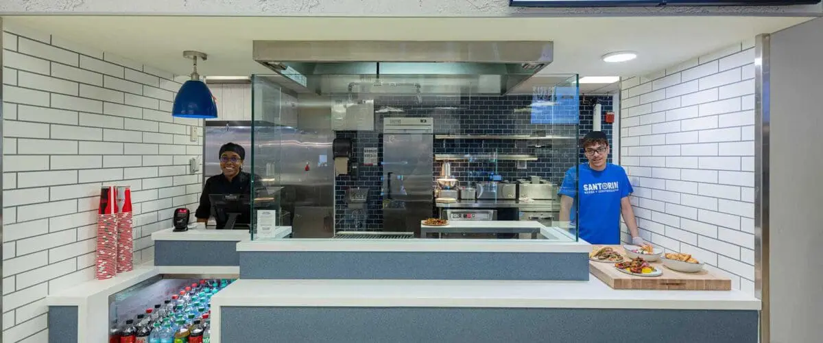 Two employees standing behind counter of Santorini